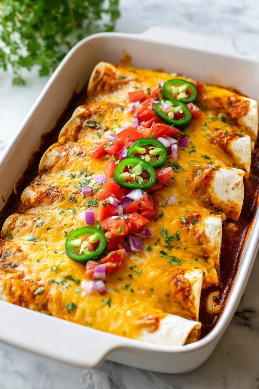 The image shows a white baking dish filled with four rolled enchiladas placed side by side. Each soft tortilla is covered with a layer of melted golden and white cheese that looks bubbly and slightly browned. The enchiladas are topped with small pieces of red tomato and purple onion, along with three green jalapeño slices placed in the middle. The edges of the tortillas are slightly crispy and the filling under the cheese is covered by a reddish sauce. The dish sits on a white marbled surface with fresh green herb leaves slightly blurred in the background. Photo taken with an iphone --ar 2:3 --v 7
