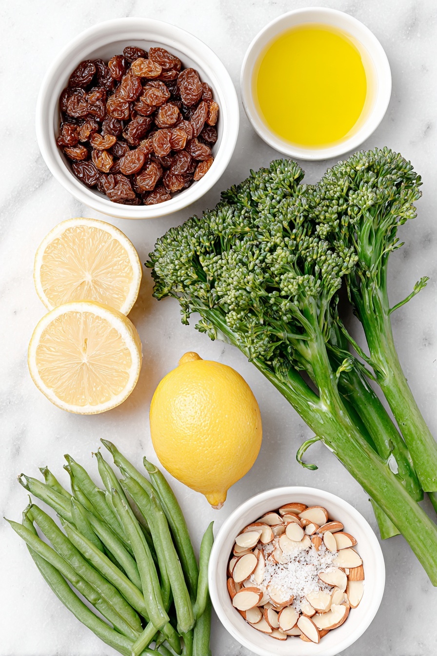 Flat lay of a small pile of dried currants in a simple white ceramic bowl, a small white bowl filled with golden olive oil, a whole lemon cut in half with a few bright yellow strips of lemon peel beside it, two whole cloves of garlic with papery skins unbroken, a bunch of fresh green broccolini with tender stalks and florets, a neat pile of fresh green beans with stems trimmed, a small white bowl of clear water, a few loose grains of sea salt and whole black peppercorns scattered artfully, a small white bowl holding toasted sliced almonds with a warm golden-brown hue, placed on a clean white marble surface, soft natural light, photo taken with an iPhone, professional food photography style, fresh ingredients, white ceramic bowls, no bottles, no duplicates, no utensils, no packaging --ar 2:3 --v 7 --p m7354615311229779997