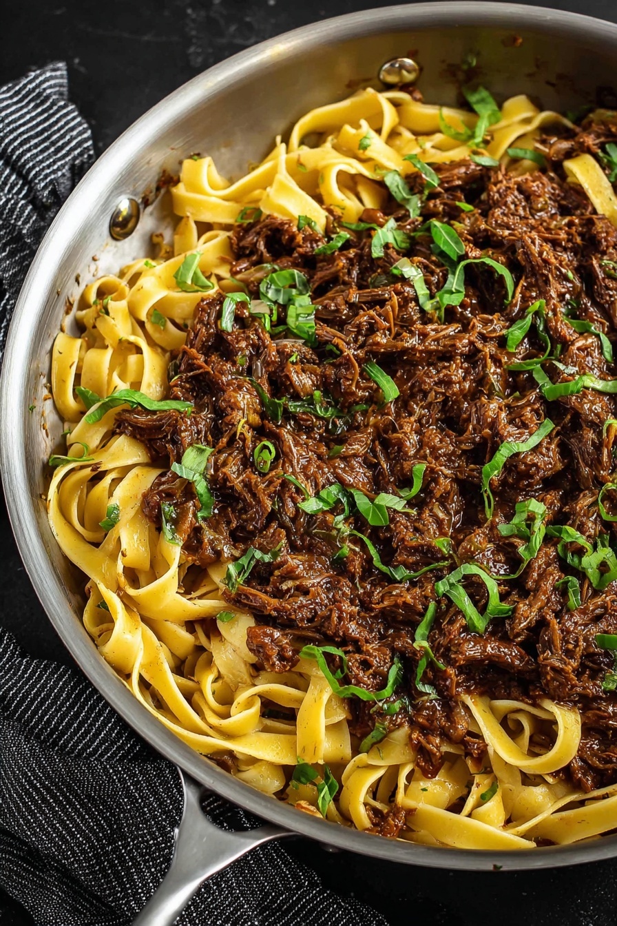 A large white bowl filled with wide, flat noodles mixed with chunks of dark brown shredded meat. The noodles are golden yellow with a slightly glossy texture, twisted and layered unevenly throughout the bowl. The dark brown meat pieces are scattered evenly among the noodles, creating a rich contrast. Small green parsley leaves are sprinkled on top, adding a fresh pop of color. Light white flakes, likely grated cheese, are scattered thinly over the whole dish. A fork is placed in the bowl on the right side, partly wrapped in noodles. In the background, a small white bowl with pale yellow cheese cubes sits on a white marbled surface. photo taken with an iphone --ar 2:3 --v 7