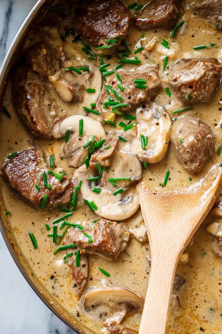 The image shows a close-up of a creamy dish in a black pan with a white marbled background. The dish has about two layers: the first layer is a light brown creamy sauce that is rich and smooth in texture, spreading over the whole pan. The second layer consists of browned pieces of meat and sliced mushrooms scattered throughout the sauce, with small green onion pieces sprinkled on top. A wooden spoon with a light natural wood grain is partially dipped into the sauce on the right side of the pan, slightly lifting some of the creamy mixture. Photo taken with an iphone --ar 2:3 --v 7
