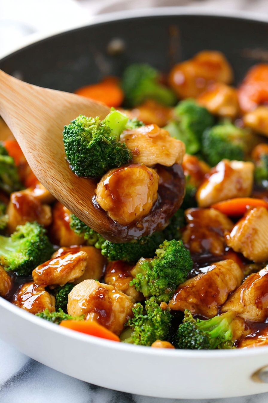 A white pan filled with bright green broccoli florets and chunks of golden-brown cooked chicken, all coated in a shiny, thick brown sauce. The broccoli has a fresh and slightly textured look, while the chicken pieces are glossy and smooth. There are also a few bright orange carrot slices mixed in. A wooden spatula is lifting some pieces of chicken and broccoli, showing the rich sauce covering them, with a white marbled surface beneath the pan photo taken with an iphone --ar 2:3 --v 7