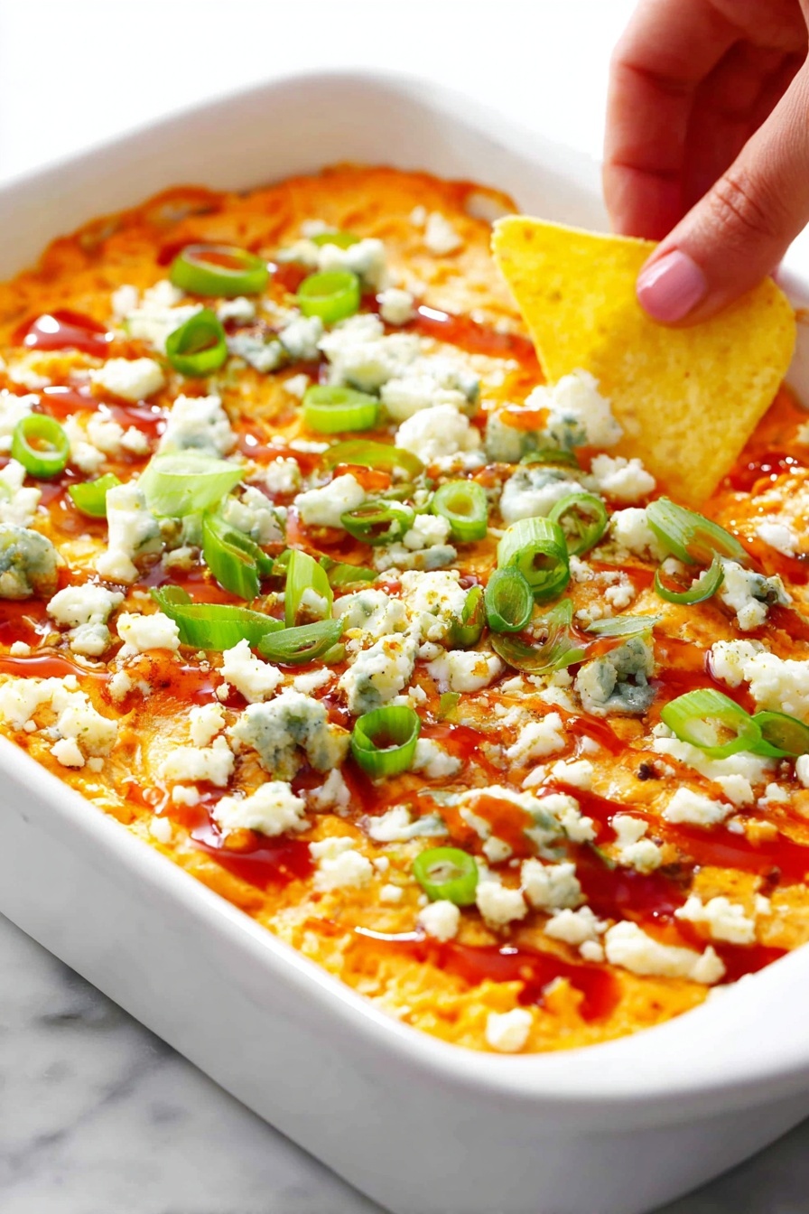 A clear glass bowl sits on a white marbled surface, filled with a creamy orange mixture that looks slightly chunky with small green flecks throughout. A red and black spatula rests inside the bowl, partially submerged in the mixture, showing a thick, textured consistency that appears slightly uneven with soft peaks and folds. The bowl is full but not overflowing, and the spatula handle stands out with its smooth, solid colors against the vibrant mixture. photo taken with an iphone --ar 2:3 --v 7